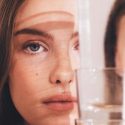 woman looking through a glass for skincare blogs about the best anti aging cream, cleansers for sensitive skin and more